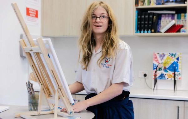 A student creating art on an easel during class.